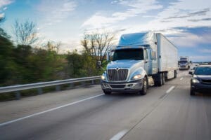 A photo of a blue truck driving fast on a highway