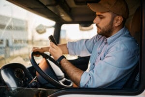 A bus driver checking his phone behind the wheel