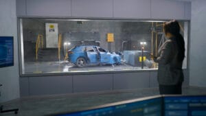 Engineer in experimental crash test laboratory watching process of traffic accident simulation, to get safety parameters of a new electro eco-friendly car body using computer system.