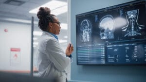 A neuroscientist analyzing brain scans on a large screen, highlighting the role of eye-tracking and biometric data in neuroscience research.